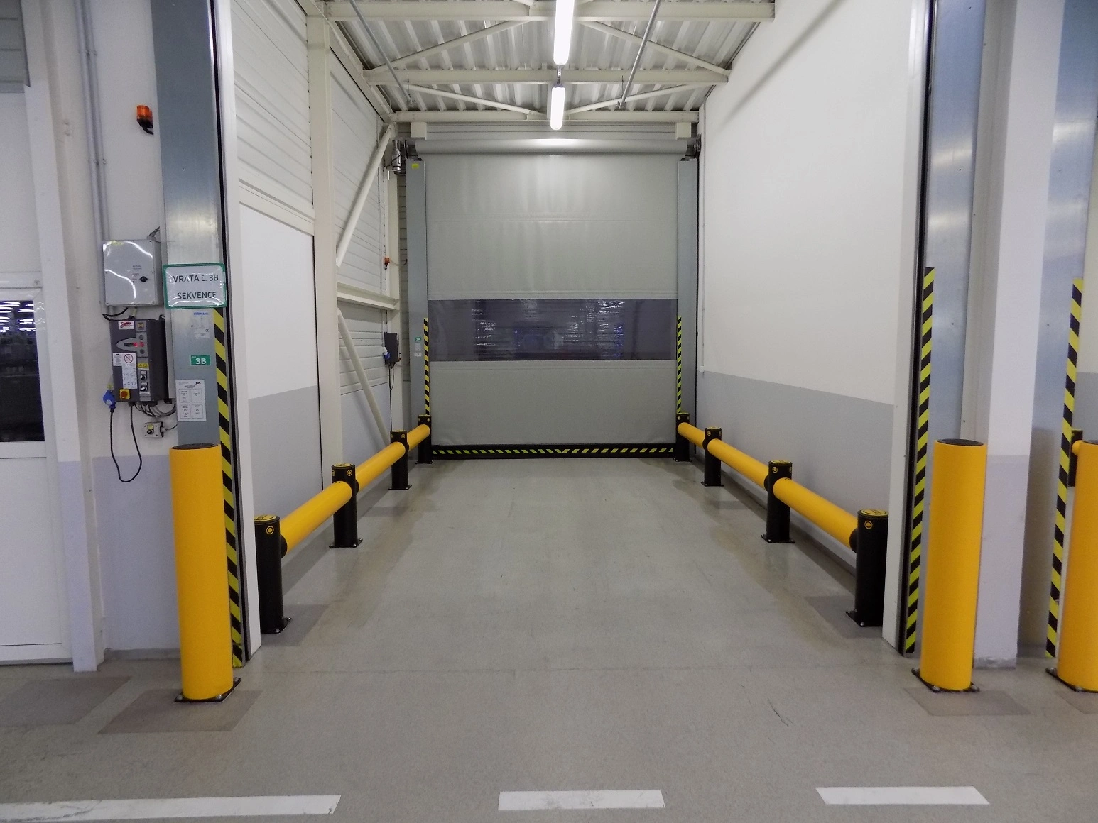 Bezpečnostní sloupky iFlex HeavyDuty Bollard od A-SAFE chrání vrata průmyslové haly před nárazy manipulační techniky.