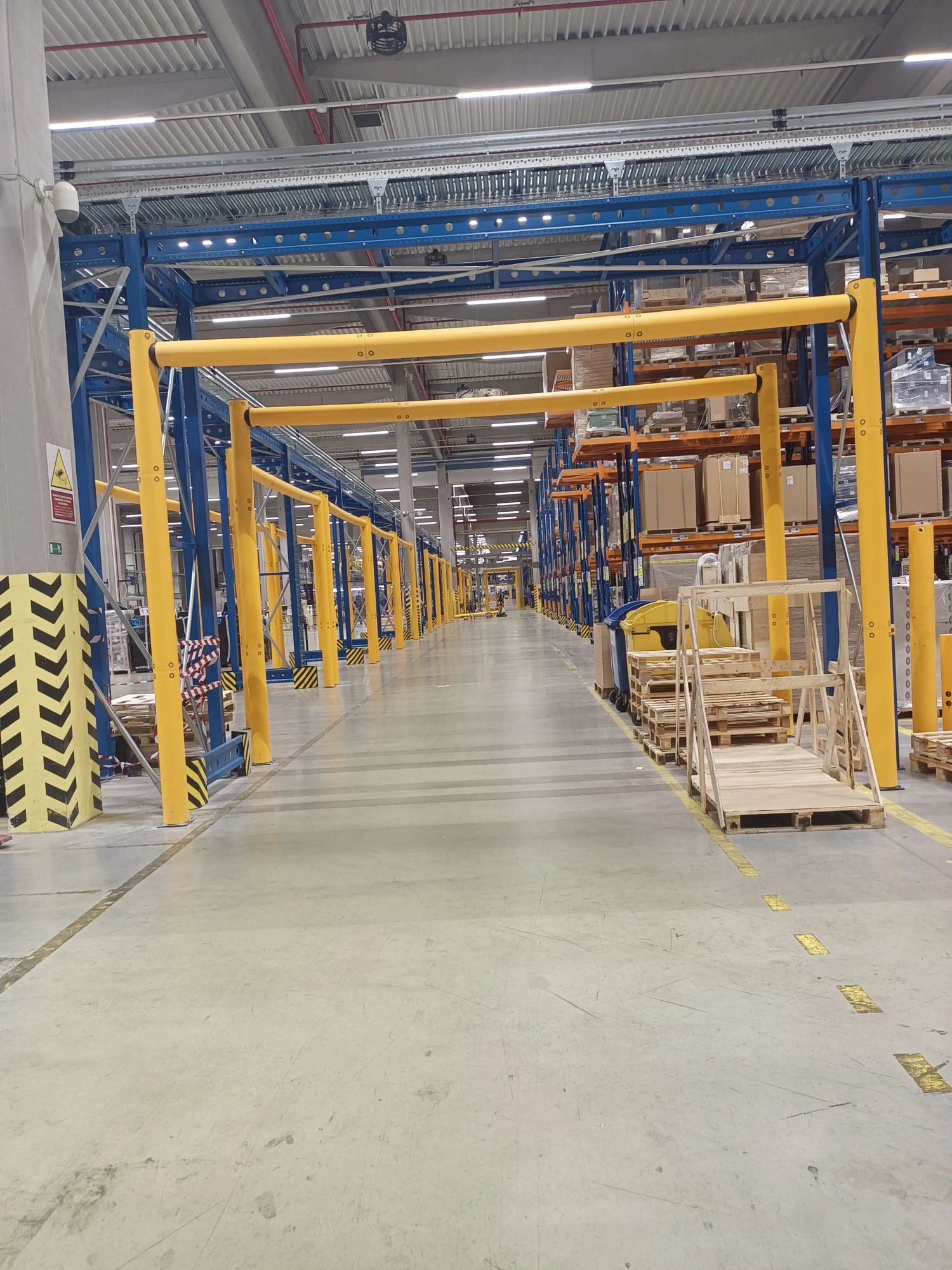 Žlutý výškový omezovač iFlex Height Restrictor chrání průjezd ve skladu před nárazy vysokozdvižných vozíků.